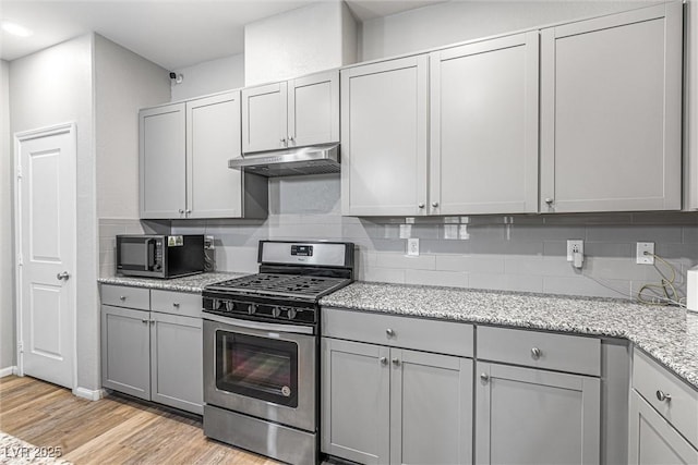 3188 Via Da Vinci, Henderson, NV 89044 - kitchen with appliances with stainless steel finishes, under cabinet range hood, gray cabinetry, and backsplash