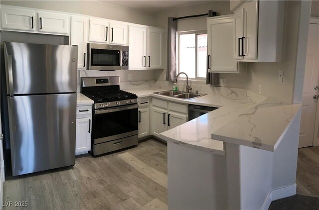 4555 E Sahara Ave Unit 226, Las Vegas, NV 89104 - kitchen featuring stainless steel appliances, a sink, a peninsula, light wood-style flooring, and white cabinetry