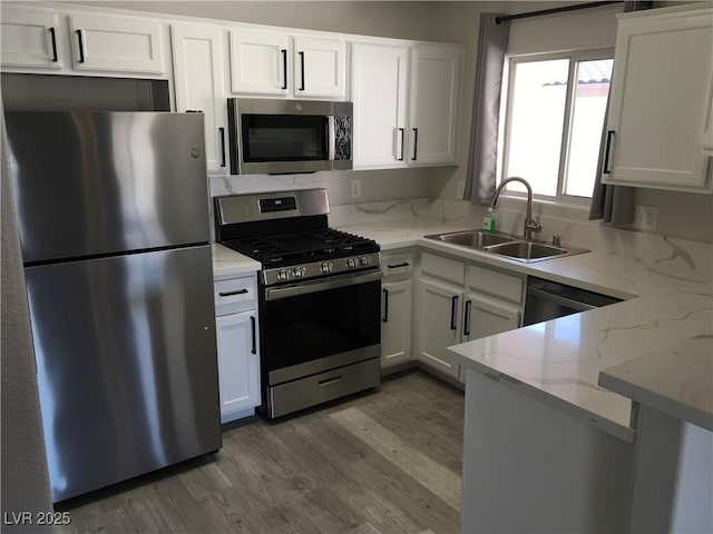 4555 E Sahara Ave Unit 226, Las Vegas, NV 89104 - kitchen with stainless steel appliances, a sink, white cabinetry, light stone counters, and wood finished floors
