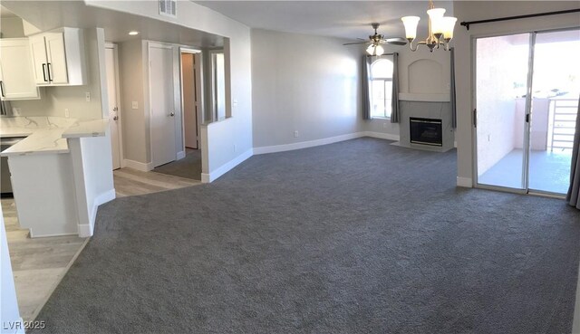 4555 E Sahara Ave Unit 226, Las Vegas, NV 89104 - unfurnished living room with light carpet, baseboards, a chandelier, ceiling fan, and a large fireplace