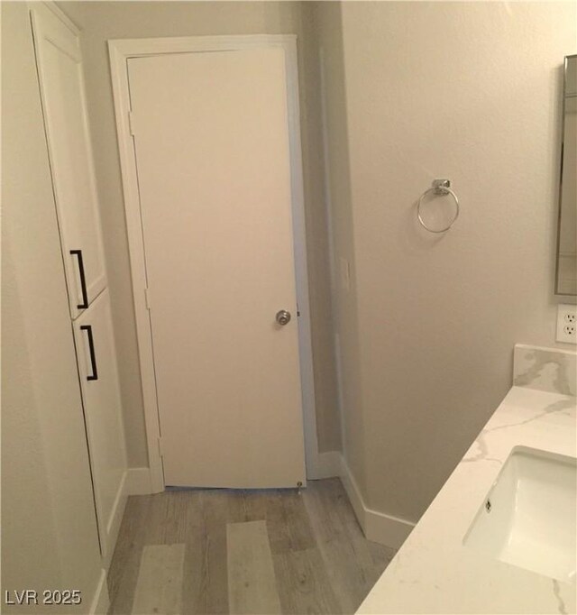 4555 E Sahara Ave Unit 226, Las Vegas, NV 89104 - bathroom featuring wood finished floors, baseboards, and double vanity