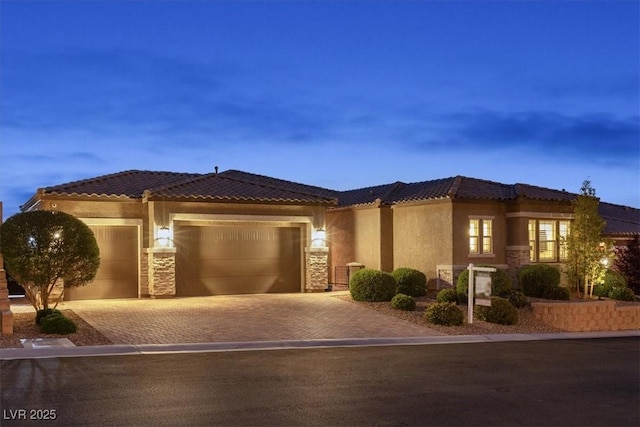 6192 Lautman Ridge Ct, Las Vegas, NV 89141 - mediterranean / spanish-style home featuring an attached garage, decorative driveway, stone siding, stucco siding, and a tile roof