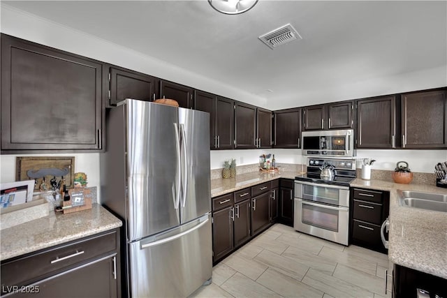 4419 Lorna Pl, Las Vegas, NV 89107 - kitchen featuring appliances with stainless steel finishes, dark brown cabinetry, a sink, and light stone counters
