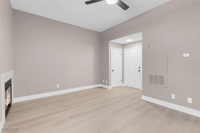 3150 Soft Breezes Dr Unit 2186, Las Vegas, NV 89128 - unfurnished living room with light wood-style flooring, ceiling fan, baseboards, and a lit fireplace
