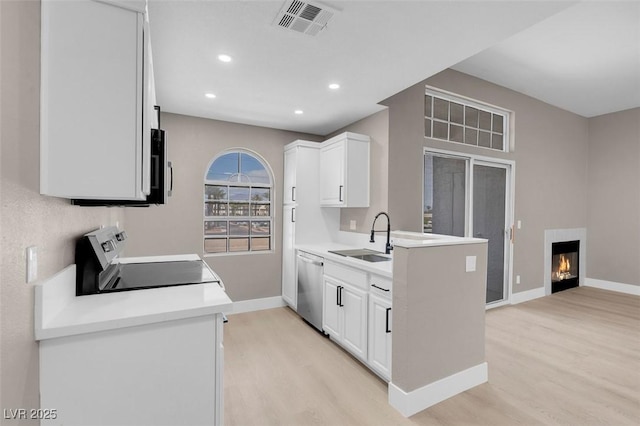 3150 Soft Breezes Dr Unit 2186, Las Vegas, NV 89128 - kitchen with stainless steel appliances, a sink, light wood finished floors, a lit fireplace, and baseboards