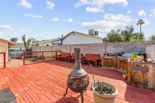 6612 Elton Ave, Las Vegas, NV 89107 - wooden terrace featuring a fire pit, a fenced backyard, exterior kitchen, and central AC unit