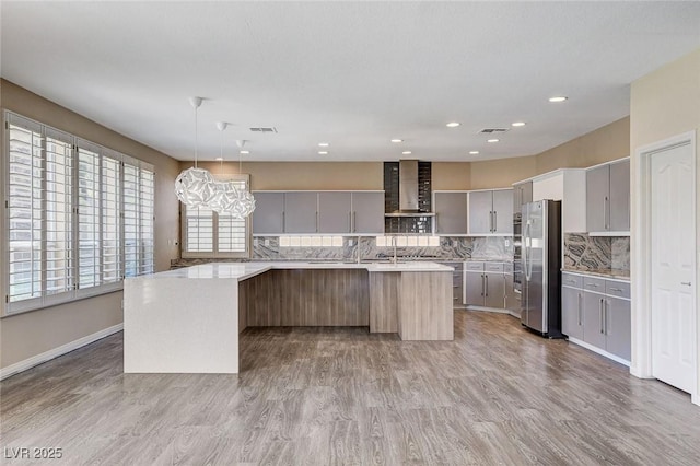 8113 Gothic Ave, Las Vegas, NV 89117 - kitchen with wall chimney range hood, freestanding refrigerator, light countertops, backsplash, and wood finished floors
