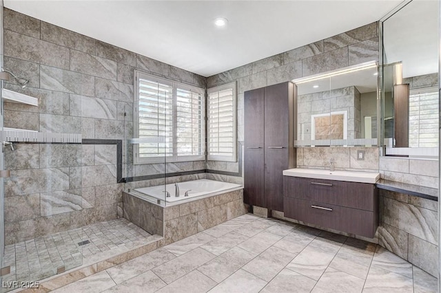 8113 Gothic Ave, Las Vegas, NV 89117 - bathroom with plenty of natural light, a bath, vanity, tile walls, and marble look tiles