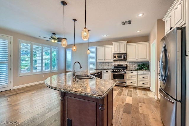 4311 Fiore Bella Blvd, Las Vegas, NV 89135 - kitchen with appliances with stainless steel finishes, ceiling fan, light wood-style floors, backsplash, and hanging light fixtures