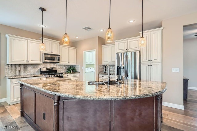 4311 Fiore Bella Blvd, Las Vegas, NV 89135 - kitchen with stainless steel appliances, independent washer and dryer, backsplash, light wood finished floors, and light stone countertops