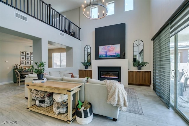 7194 Sage Wren Ct, Las Vegas, NV 89148 - living room featuring a high ceiling, a glass covered fireplace, a chandelier, and light wood-style floors