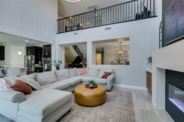 7194 Sage Wren Ct, Las Vegas, NV 89148 - living room featuring stairway, a high ceiling, a chandelier, and baseboards