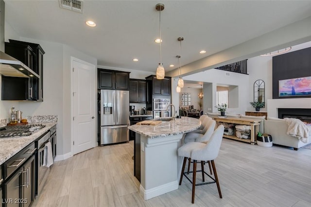 7194 Sage Wren Ct, Las Vegas, NV 89148 - kitchen with appliances with stainless steel finishes, open floor plan, a kitchen breakfast bar, light stone counters, and recessed lighting
