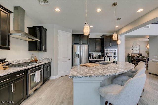 7194 Sage Wren Ct, Las Vegas, NV 89148 - kitchen with appliances with stainless steel finishes, wall chimney exhaust hood, a sink, light stone countertops, and pendant lighting