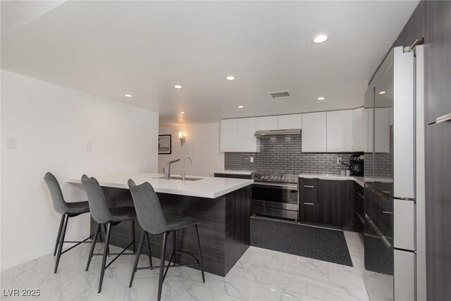 3111 Bel Air Dr Unit 12G, Las Vegas, NV 89109 - kitchen featuring stainless steel range with electric stovetop, modern cabinets, a sink, a breakfast bar, and recessed lighting