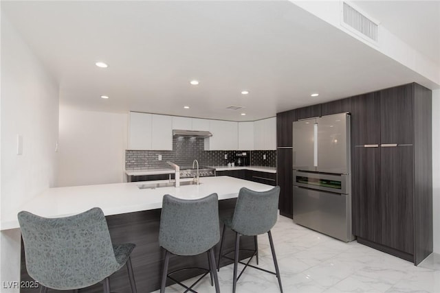 3111 Bel Air Dr Unit 12G, Las Vegas, NV 89109 - kitchen featuring freestanding refrigerator, modern cabinets, a sink, a kitchen bar, and light marble finish floors