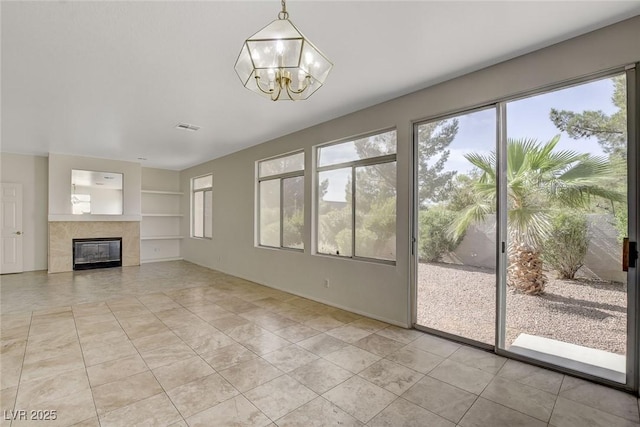 1408 Reebok Ter, Henderson, NV 89014 - unfurnished living room with built in features, light tile patterned floors, a chandelier, a tiled fireplace, and baseboards
