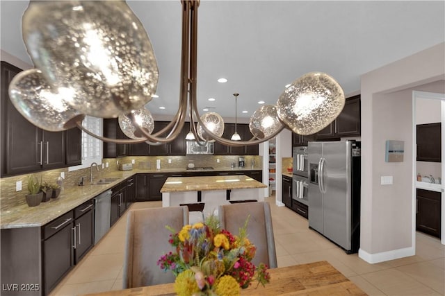 5542 Oak Bend Dr, Las Vegas, NV 89135 - kitchen featuring appliances with stainless steel finishes, decorative backsplash, a center island, light tile patterned flooring, and light stone counters