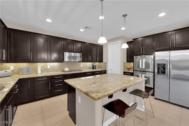 5542 Oak Bend Dr, Las Vegas, NV 89135 - kitchen featuring appliances with stainless steel finishes, light stone counters, a center island, dark brown cabinets, and recessed lighting