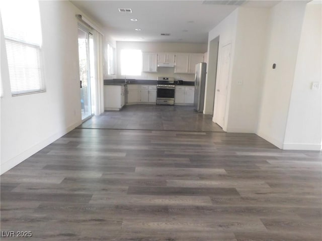 11173 Hickory Glen St, Las Vegas, NV 89179 - kitchen with stainless steel appliances, dark countertops, open floor plan, under cabinet range hood, and white cabinets