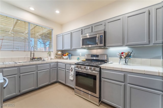 2789 Trotwood Ln, Las Vegas, NV 89108 - kitchen with stainless steel appliances, gray cabinetry, a sink, tile countertops, and recessed lighting