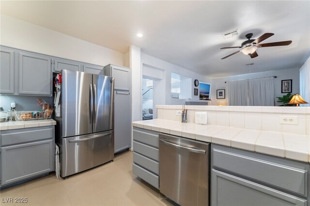2789 Trotwood Ln, Las Vegas, NV 89108 - kitchen with stainless steel appliances, tile counters, and gray cabinetry