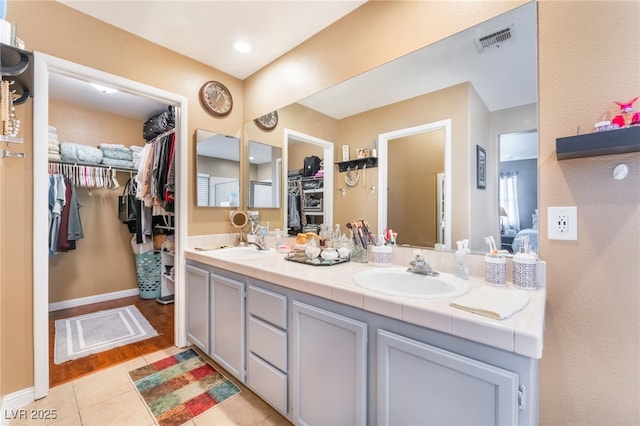 2789 Trotwood Ln, Las Vegas, NV 89108 - bathroom with double vanity, tile patterned flooring, a walk in closet, and baseboards