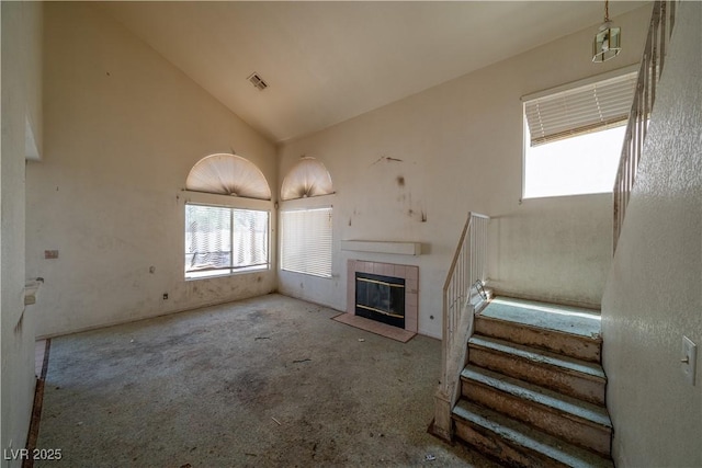 1436 Padre Bay Dr, Las Vegas, NV 89108 - unfurnished living room with healthy amount of natural light, high vaulted ceiling, stairway, carpet floors, and a fireplace
