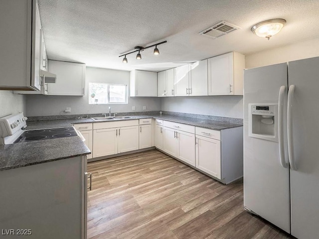 2713 Valley St, Las Vegas, NV 89101 - kitchen with white appliances, a textured ceiling, a sink, light wood finished floors, and white cabinets