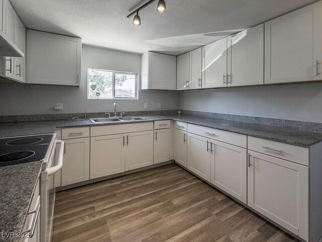 2713 Valley St, Las Vegas, NV 89101 - kitchen featuring wall chimney exhaust hood, a sink, a textured ceiling, white range with electric stovetop, and dark countertops