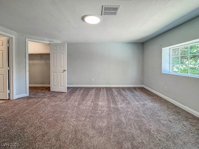 2713 Valley St, Las Vegas, NV 89101 - unfurnished bedroom with a textured ceiling, carpet floors, a walk in closet, baseboards, and a closet