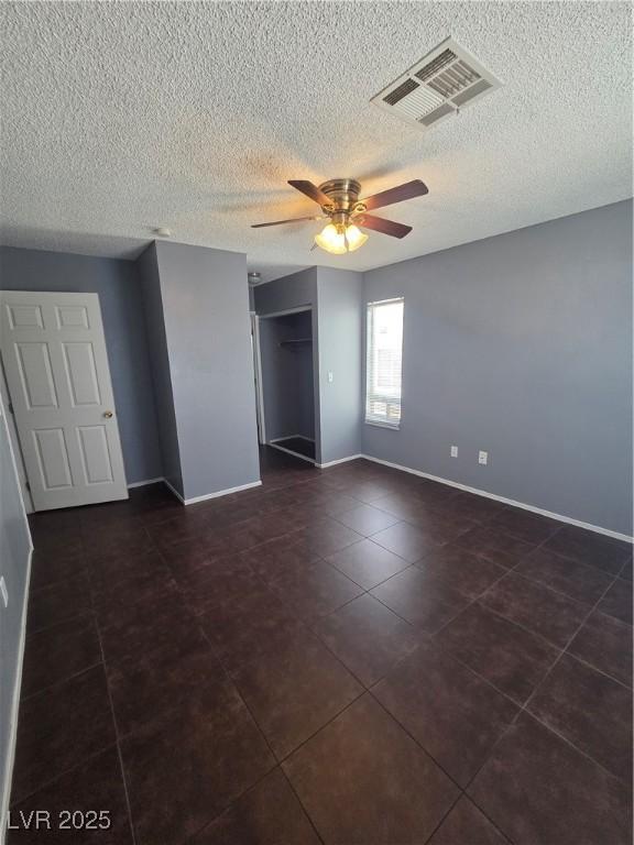 7100 Pirates Cove Rd Unit 1099, Las Vegas, NV 89145 - unfurnished bedroom featuring baseboards, a textured ceiling, a closet, dark tile patterned flooring, and a ceiling fan
