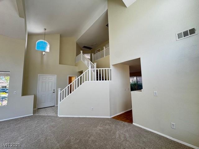 2419 Pebble Springs Ct, Henderson, NV 89074 - unfurnished living room featuring carpet floors, stairway, and a towering ceiling