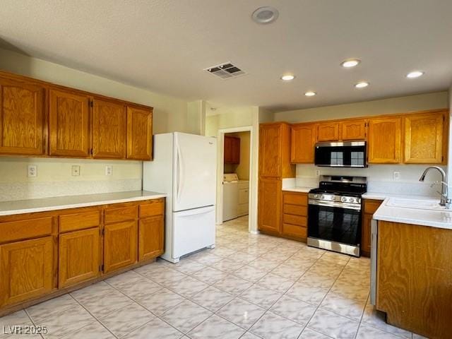 2419 Pebble Springs Ct, Henderson, NV 89074 - kitchen featuring stainless steel appliances, brown cabinets, light countertops, recessed lighting, and washer / clothes dryer