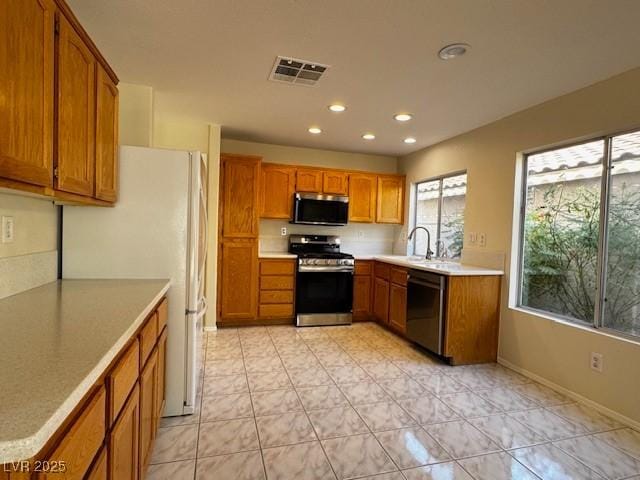 2419 Pebble Springs Ct, Henderson, NV 89074 - kitchen featuring appliances with stainless steel finishes, brown cabinetry, recessed lighting, and light countertops