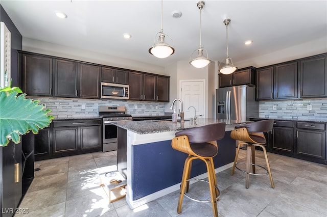 7732 Bandon Cliffs St, North Las Vegas, NV 89084 - kitchen featuring appliances with stainless steel finishes, dark stone countertops, backsplash, a kitchen bar, and dark brown cabinetry