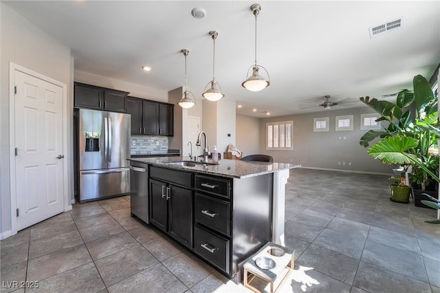 7732 Bandon Cliffs St, North Las Vegas, NV 89084 - kitchen with stainless steel appliances, dark stone countertops, decorative backsplash, a ceiling fan, and open floor plan