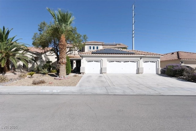 1306 Big Tree Ave, North Las Vegas, NV 89031 - mediterranean / spanish-style house with a garage, a tile roof, roof mounted solar panels, stucco siding, and driveway