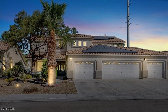1306 Big Tree Ave, North Las Vegas, NV 89031 - mediterranean / spanish home featuring driveway, an attached garage, stucco siding, a tile roof, and roof mounted solar panels