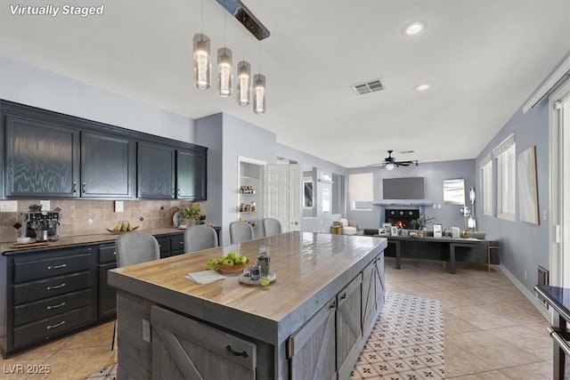1306 Big Tree Ave, North Las Vegas, NV 89031 - kitchen with ceiling fan, wood counters, a warm lit fireplace, tasteful backsplash, and light tile patterned flooring