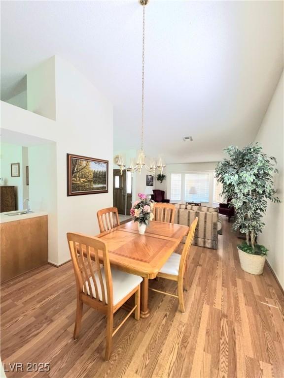 1536 Brocado Ln, Las Vegas, NV 89117 - dining space featuring light wood finished floors, a chandelier, and high vaulted ceiling