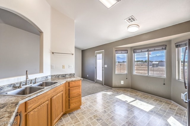 861 S Ford Loop, Pahrump, NV 89048 - kitchen with a sink, brown cabinetry, arched walkways, stainless steel dishwasher, and light countertops