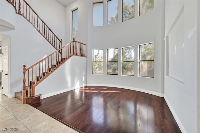 9008 Sawhill Pond St, Las Vegas, NV 89131 - unfurnished living room with a high ceiling, stairway, baseboards, and wood finished floors