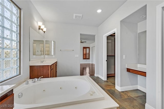 9008 Sawhill Pond St, Las Vegas, NV 89131 - full bathroom featuring stone tile floors, a whirlpool tub, vanity, a ceiling fan, and baseboards