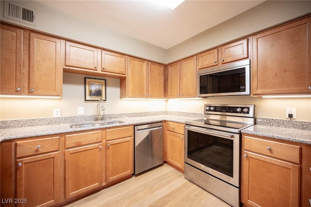 794 Oakmont Ave Unit 106, Las Vegas, NV 89109 - kitchen with stainless steel appliances, a sink, light wood finished floors, and light stone countertops