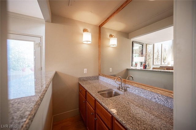 794 Oakmont Ave Unit 106, Las Vegas, NV 89109 - kitchen featuring a sink, brown cabinets, light stone countertops, baseboards, and dark wood-style floors