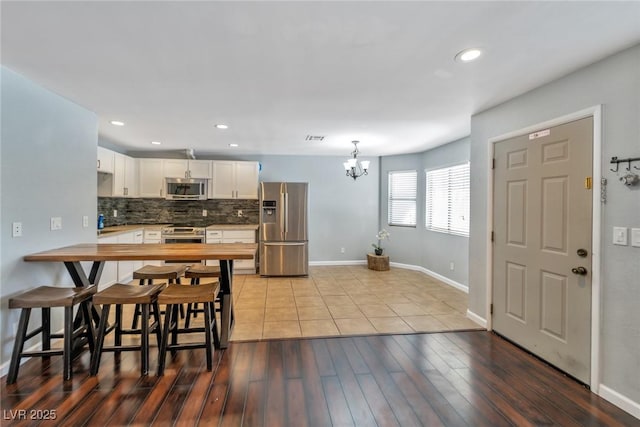 2708 Beaver Creek Ct Unit 202, Las Vegas, NV 89117 - kitchen with appliances with stainless steel finishes, a chandelier, decorative backsplash, white cabinetry, and baseboards