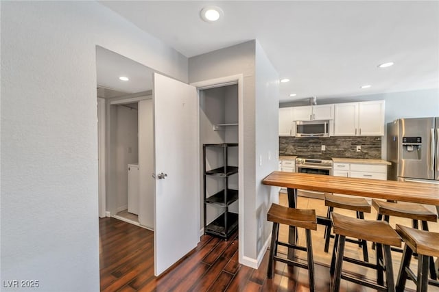 2708 Beaver Creek Ct Unit 202, Las Vegas, NV 89117 - kitchen featuring stainless steel appliances, dark wood-style floors, decorative backsplash, light countertops, and white cabinetry