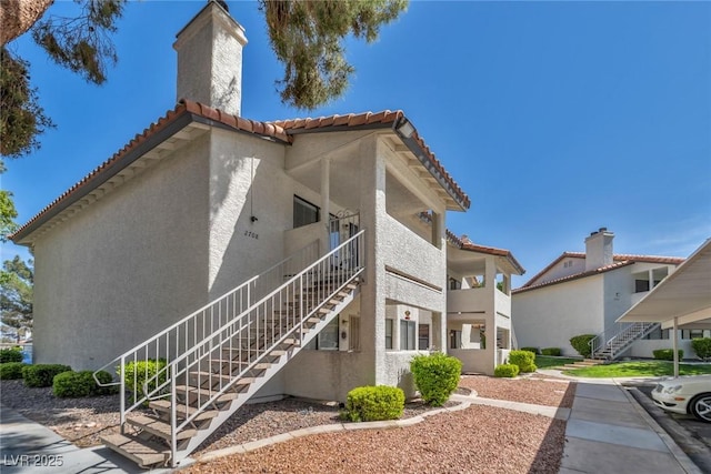 2708 Beaver Creek Ct Unit 202, Las Vegas, NV 89117 - view of side of property featuring stairs, stucco siding, a tile roof, and a chimney