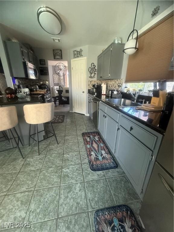 444 Viewmont Dr, Henderson, NV 89015 - kitchen featuring dark countertops, stainless steel appliances, decorative backsplash, a sink, and dark tile patterned flooring